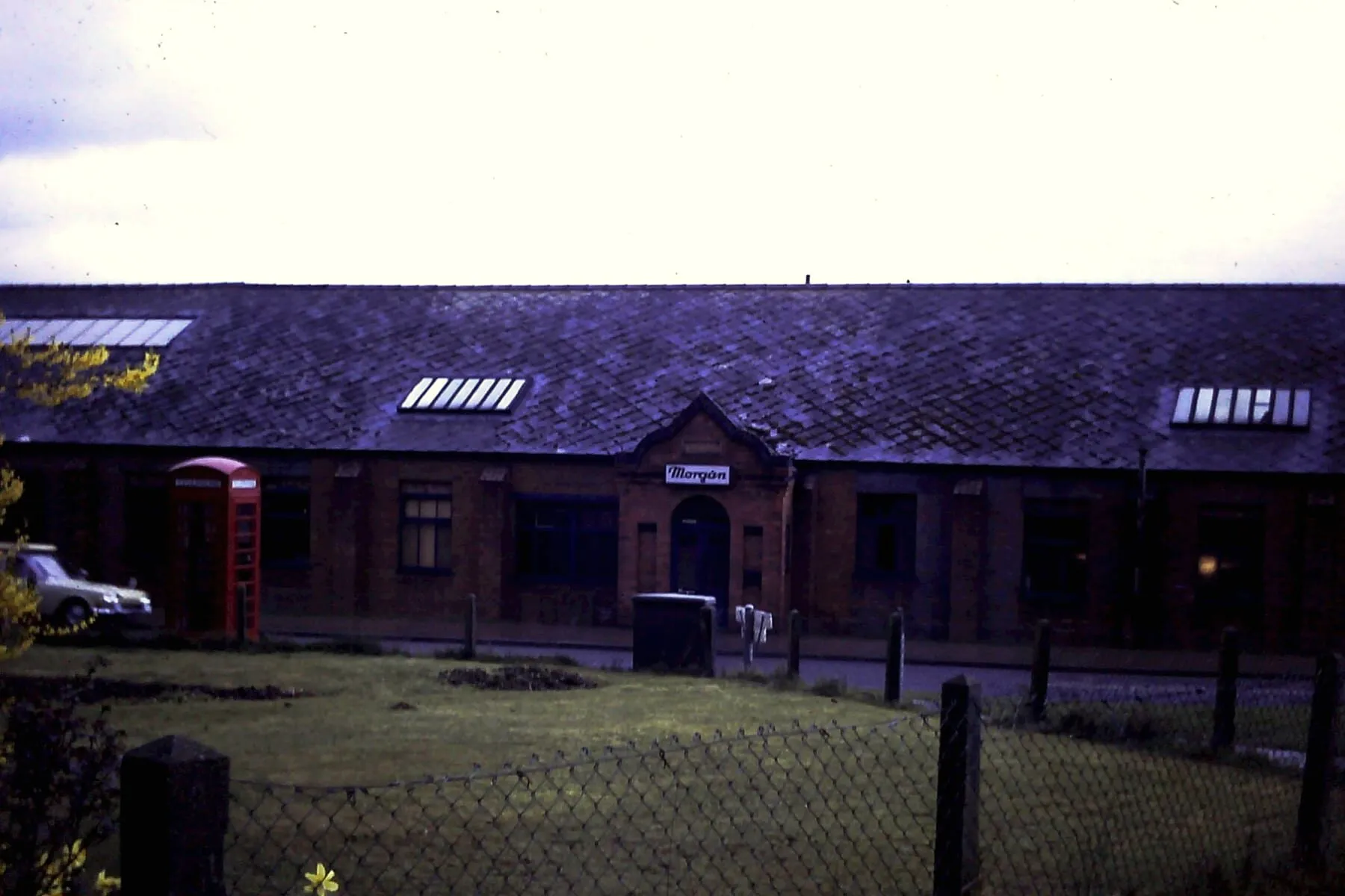 The front of the Morgan works, with a car and a red telephone box beside the entrance