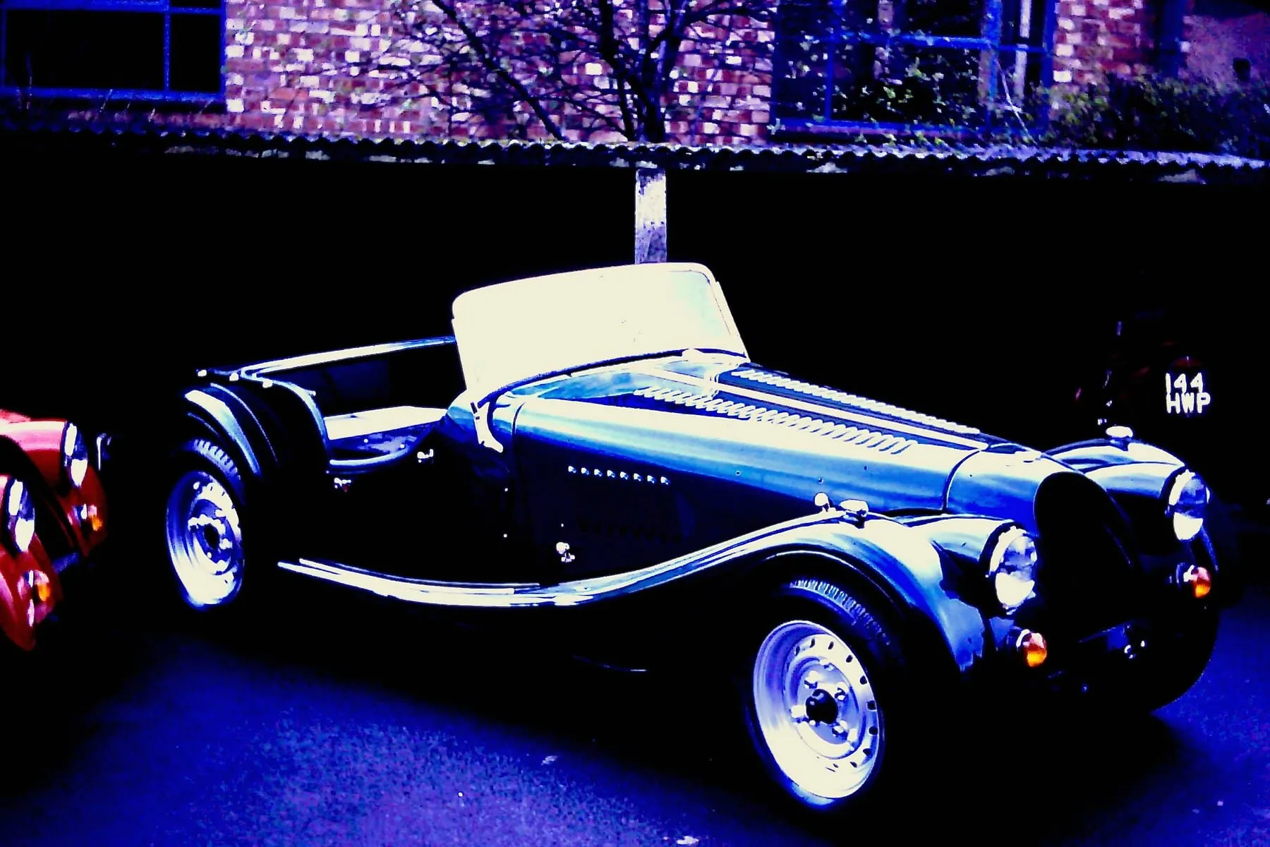 A light-coloured Morgan on the factory floor, seen from the front