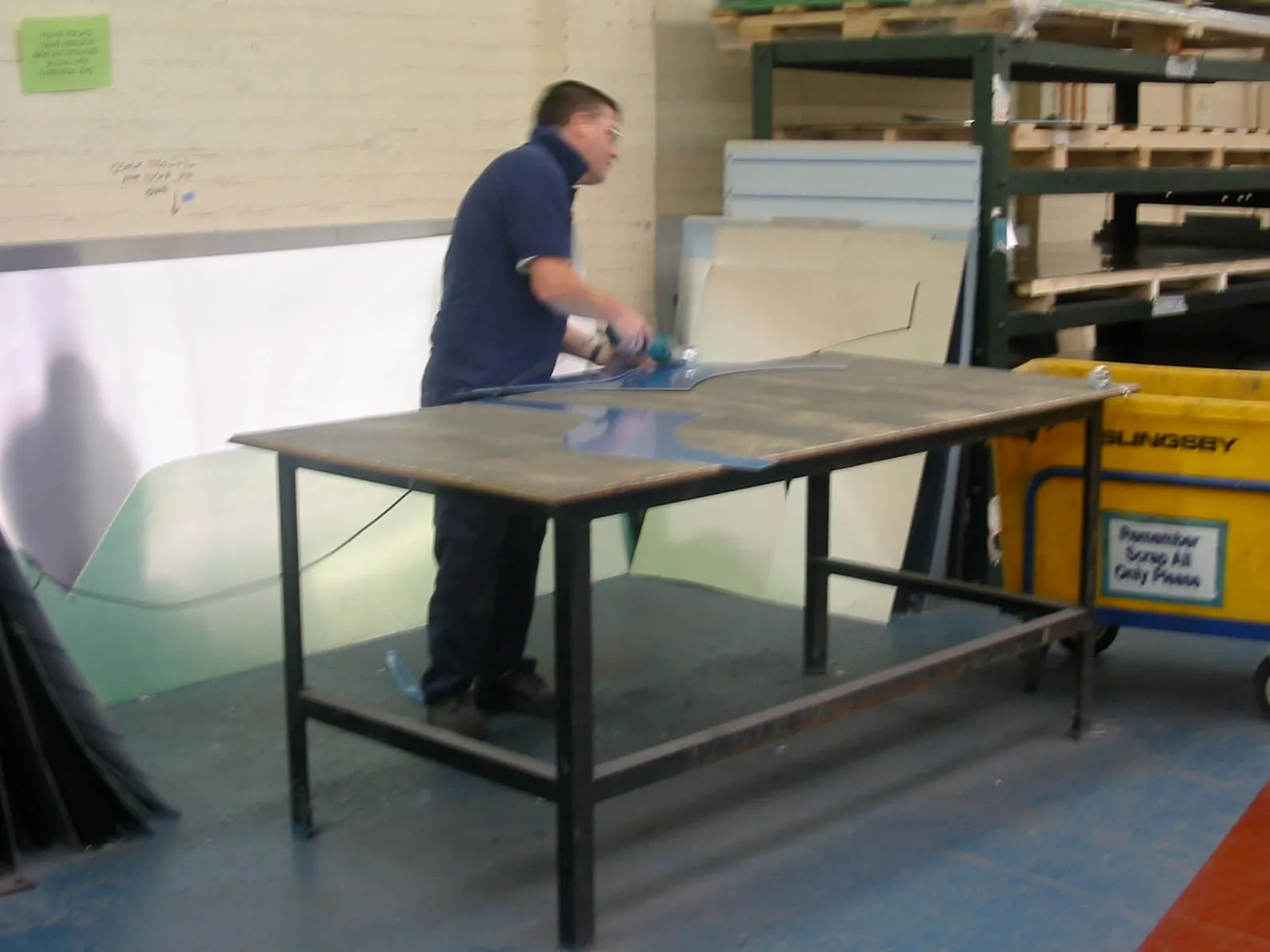 A workman cutting an aluminium sheet on a bench