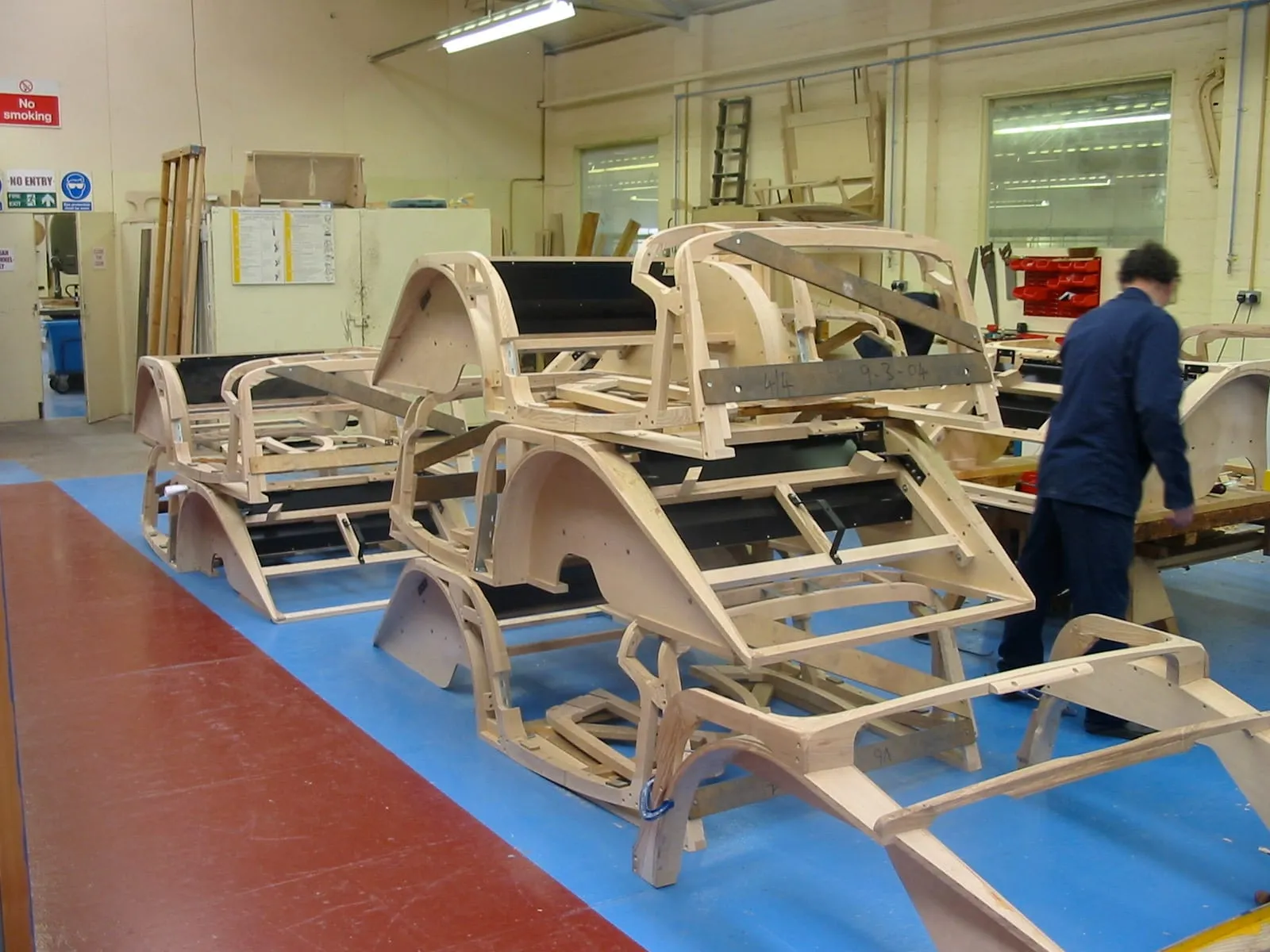 Rows of wooden frames and wheel arches in the frame shop, a workman at the back