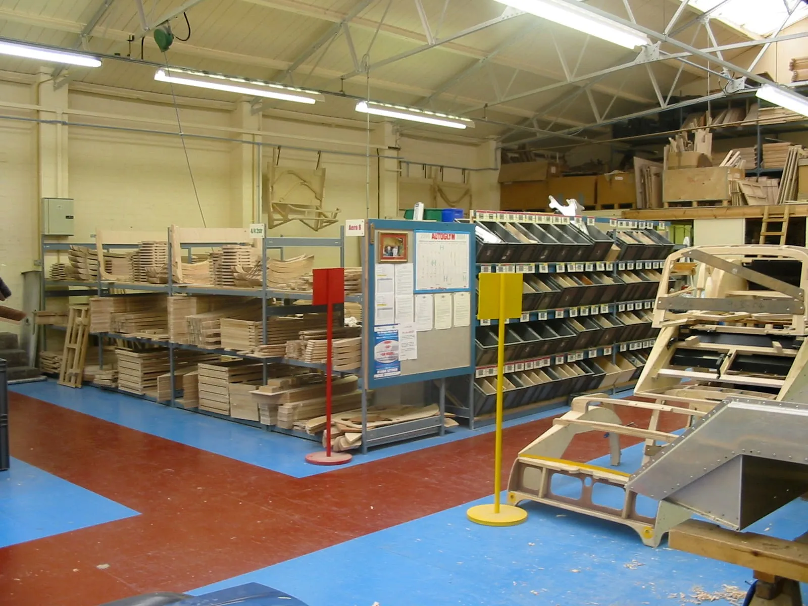 A long workshop with wooden frames in front and racks of timber behind