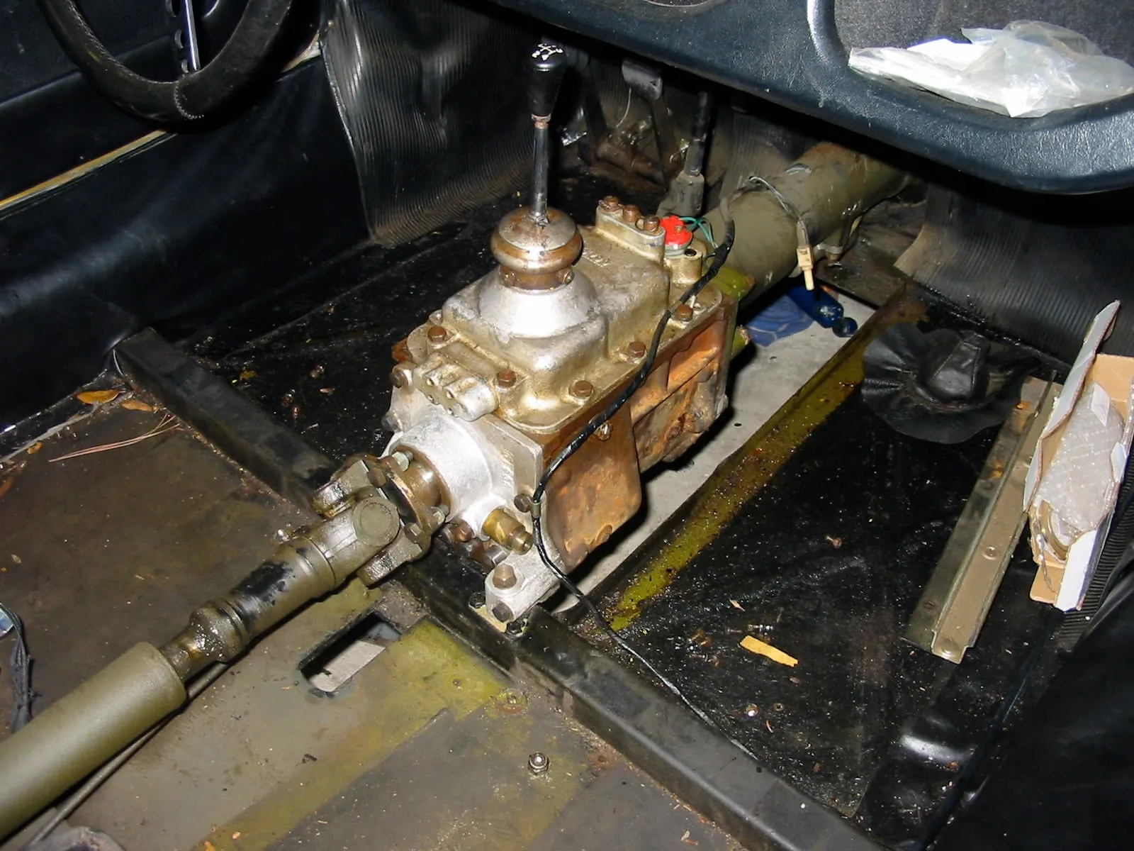 A brass-coloured Moss four-speed gearbox with its gear lever, seen through the floor of a Morgan