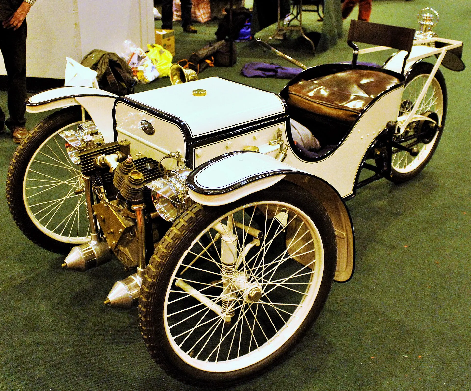 A dark-green 1911 Morgan Runabout three-wheeler on display, its V-twin engine exposed at the front