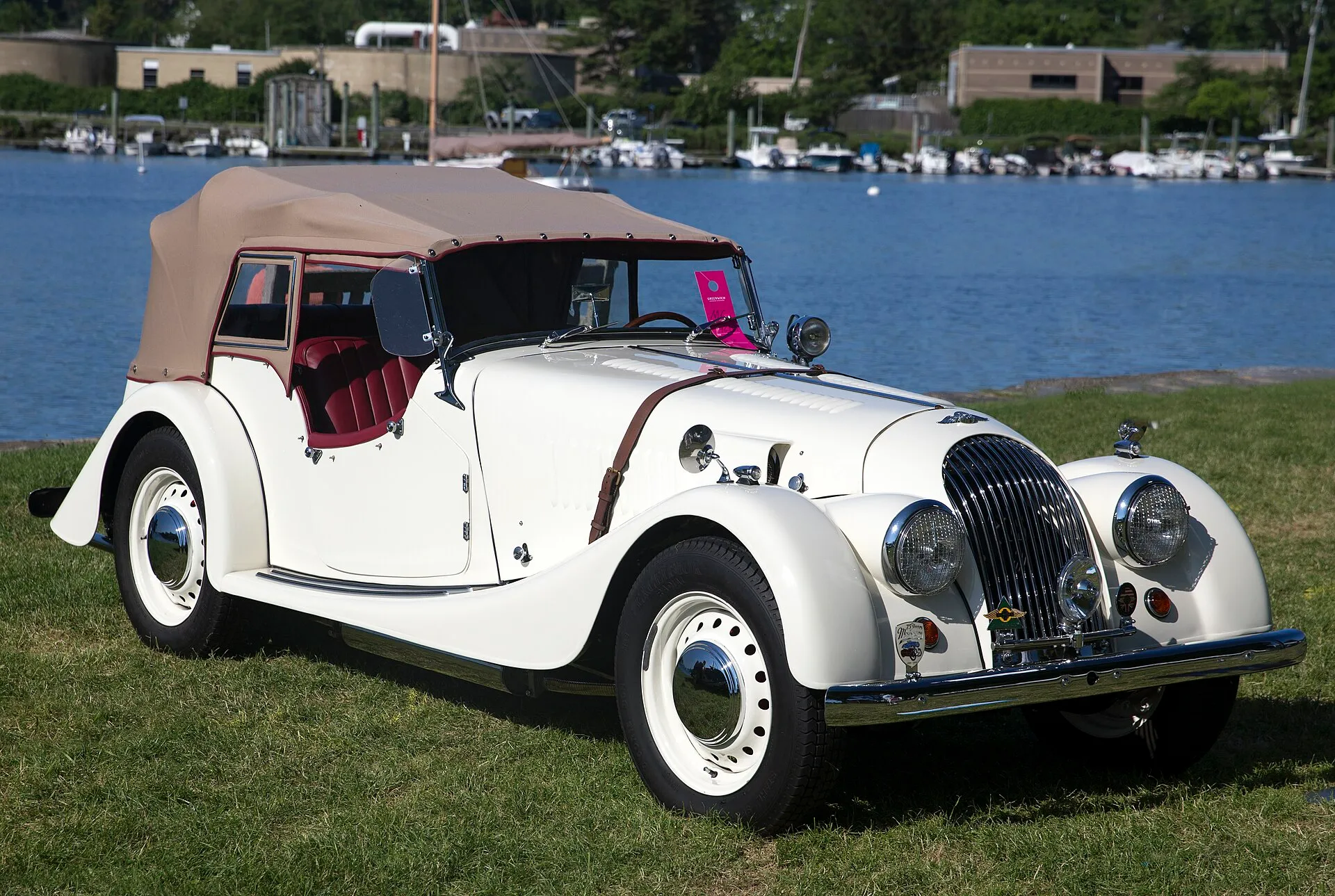 A cream 1957 Morgan Plus 4 four-seater with the cowled radiator, on a lawn