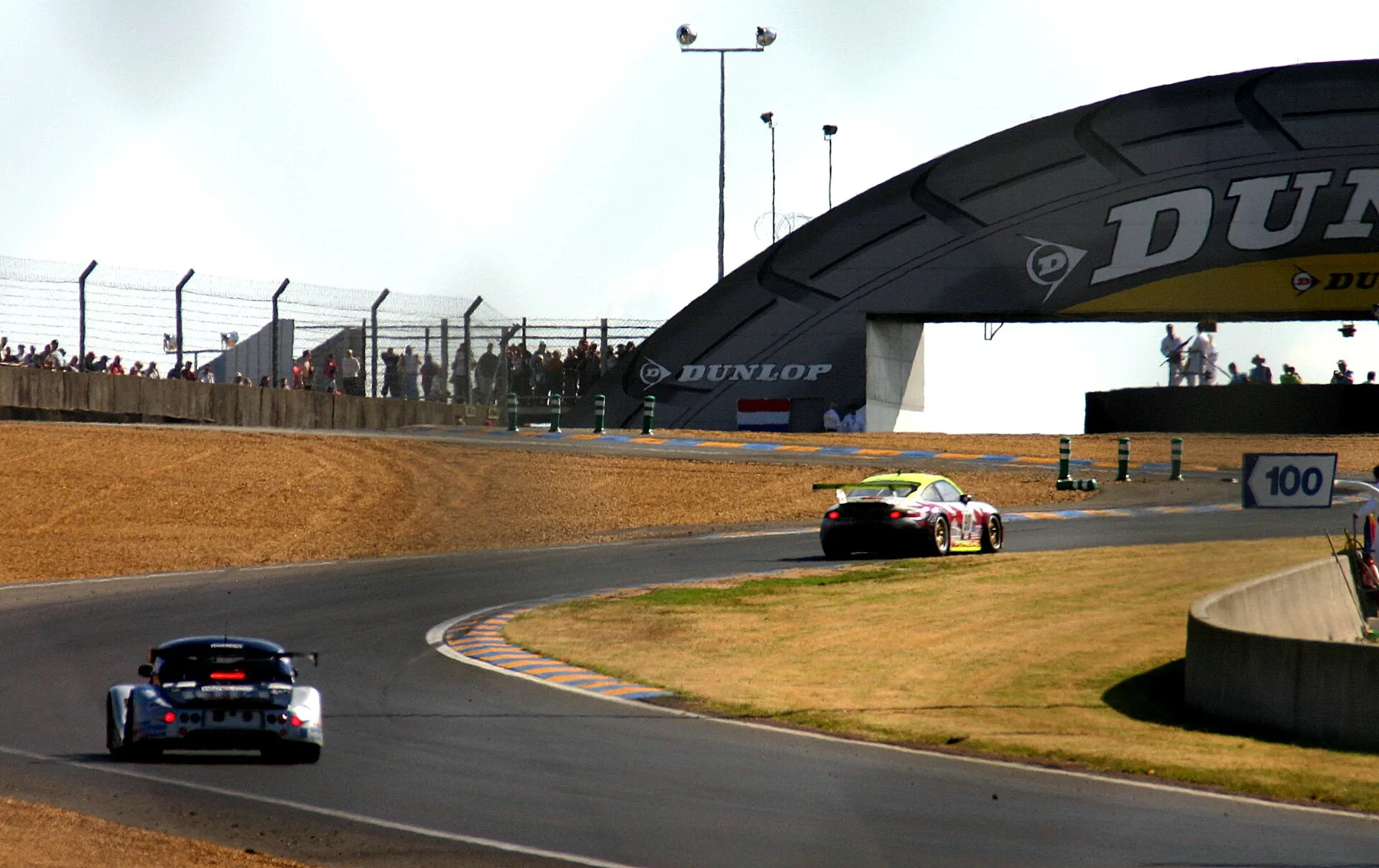 A silver Morgan Aero 8 racing car following a Porsche into the Dunlop Chicane at Le Mans, 2004