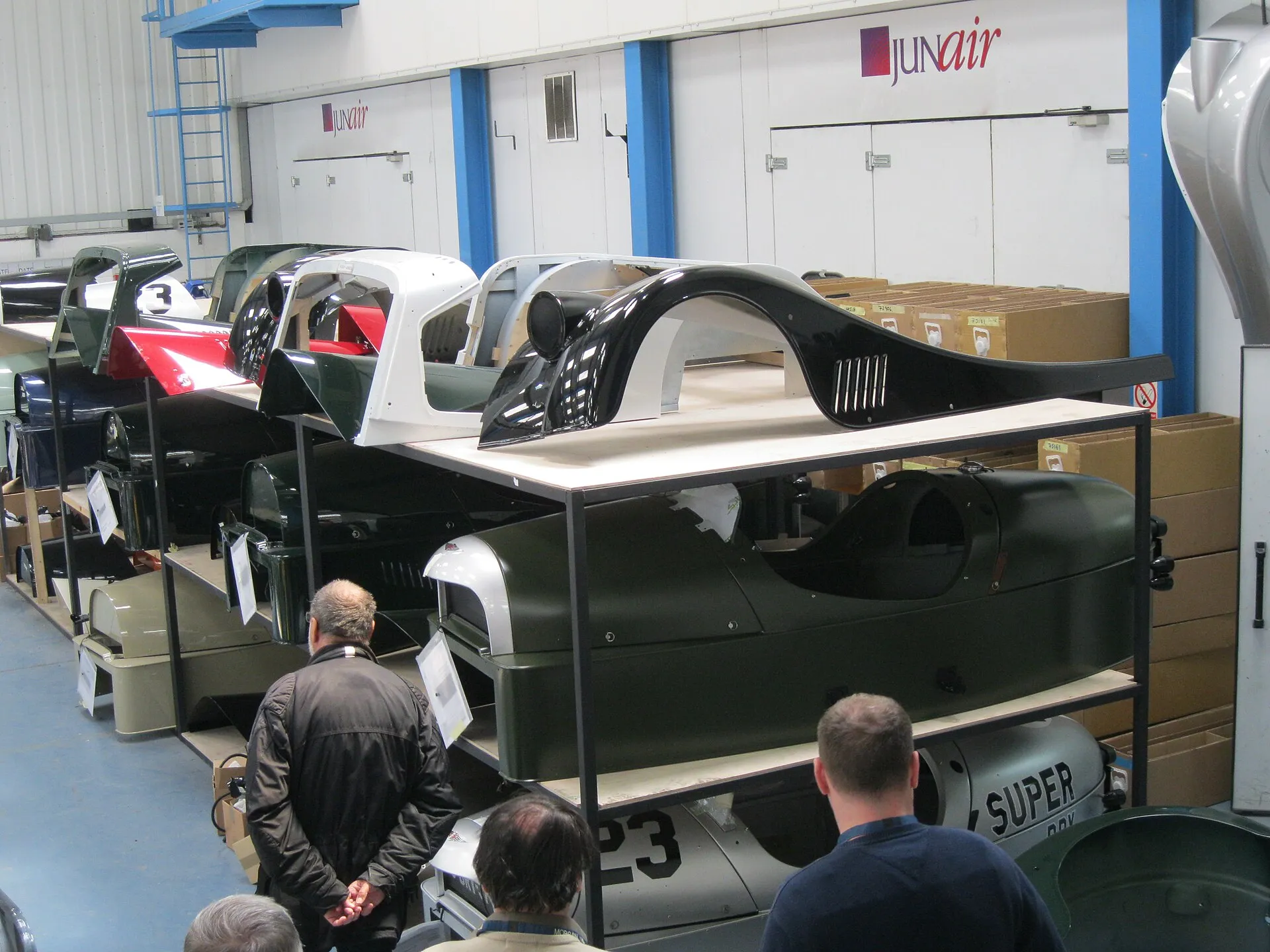 Partly built Morgan 3 Wheelers in the factory, with people looking on