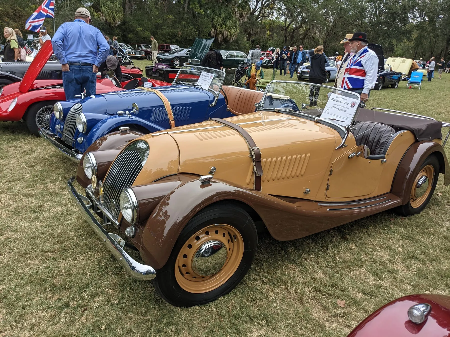 The same tan and brown 1954 Plus 4 four-seater from the side, with a dark blue Morgan beside it
