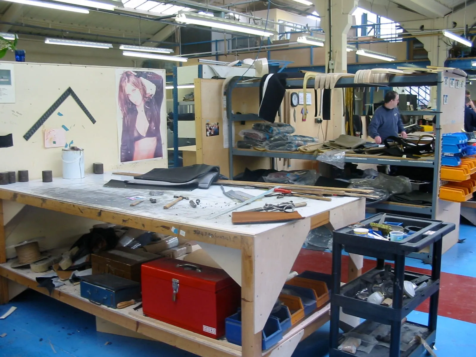 A workbench in the upholstery shop, with tools, seat frames and racks of material