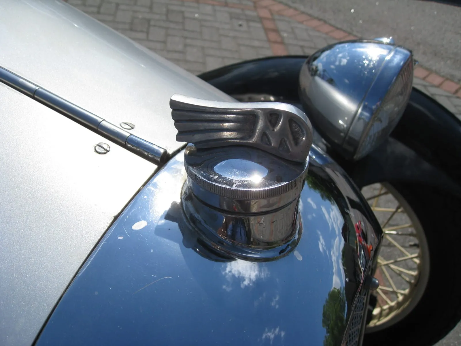 A winged M radiator cap on the bonnet of a dark three-wheeler