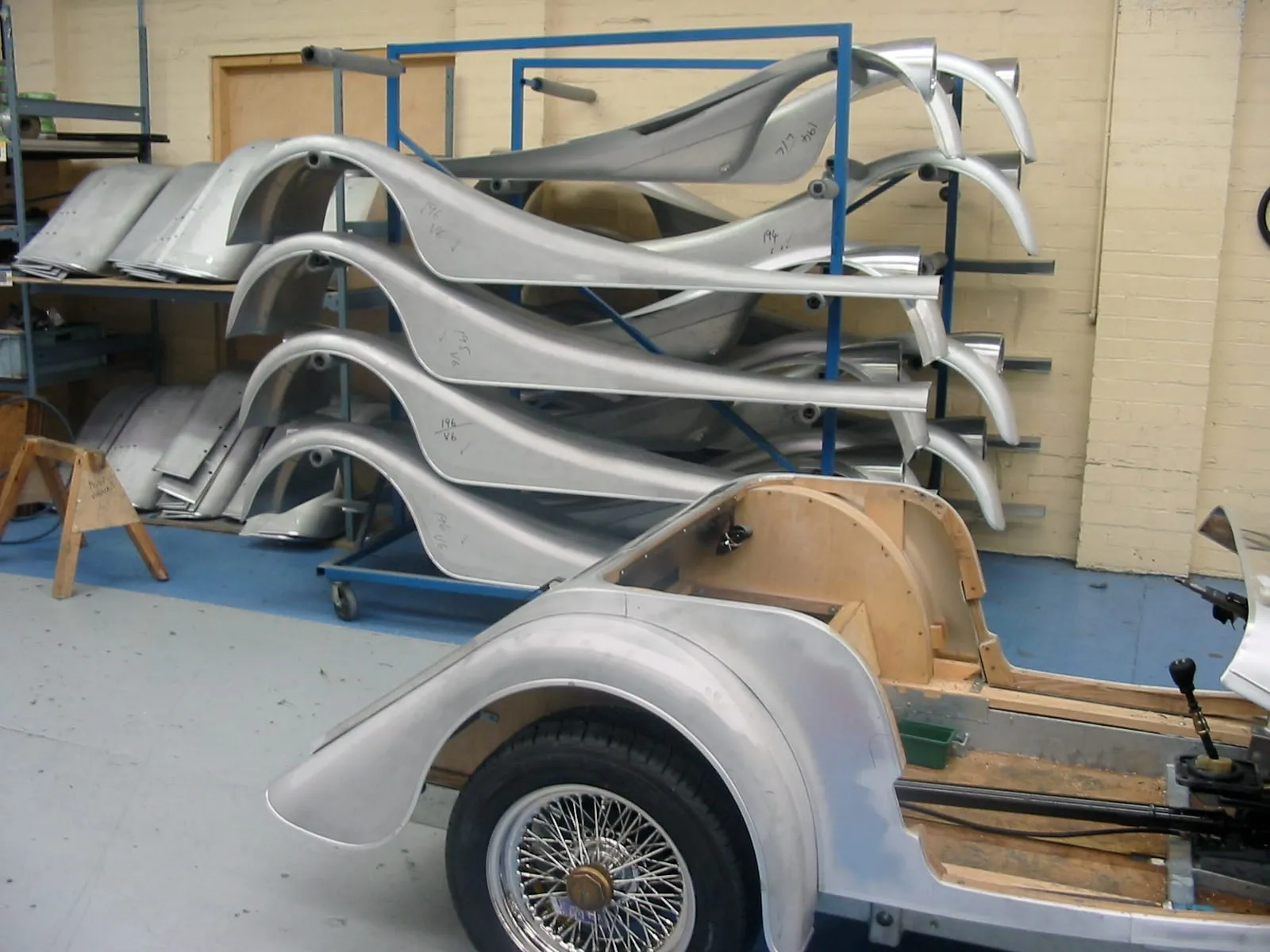 Racks of aluminium wings beside a half-built Morgan with wire wheels