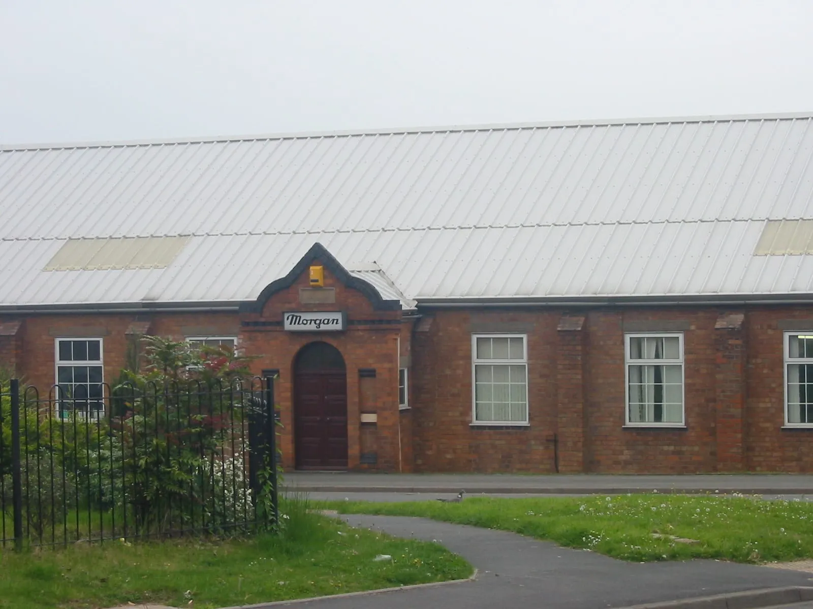 The red-brick front of the Morgan works at Malvern Link, with a Morgan sign above an arched door